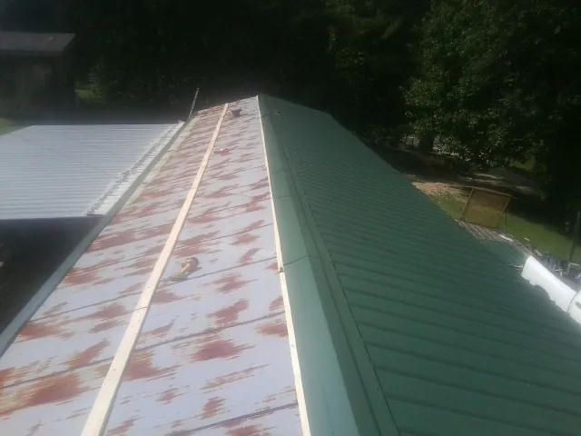 Old rusted panels beside newly installed green metal roofing — Wind Damage Roof Repair by Roofing Brothers in Centralia