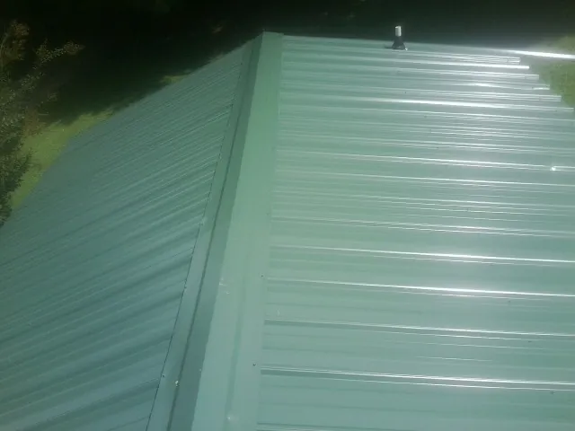 New green metal panels meeting at the ridge of a roof — Flat Roof Repair work by our crew in Centralia
