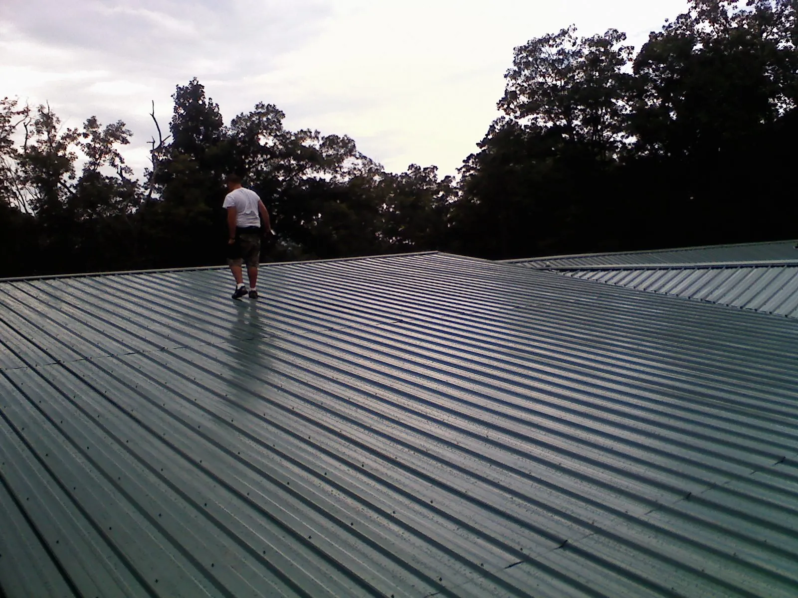 Roofer walking a wide expanse of new green metal roofing in Centralia