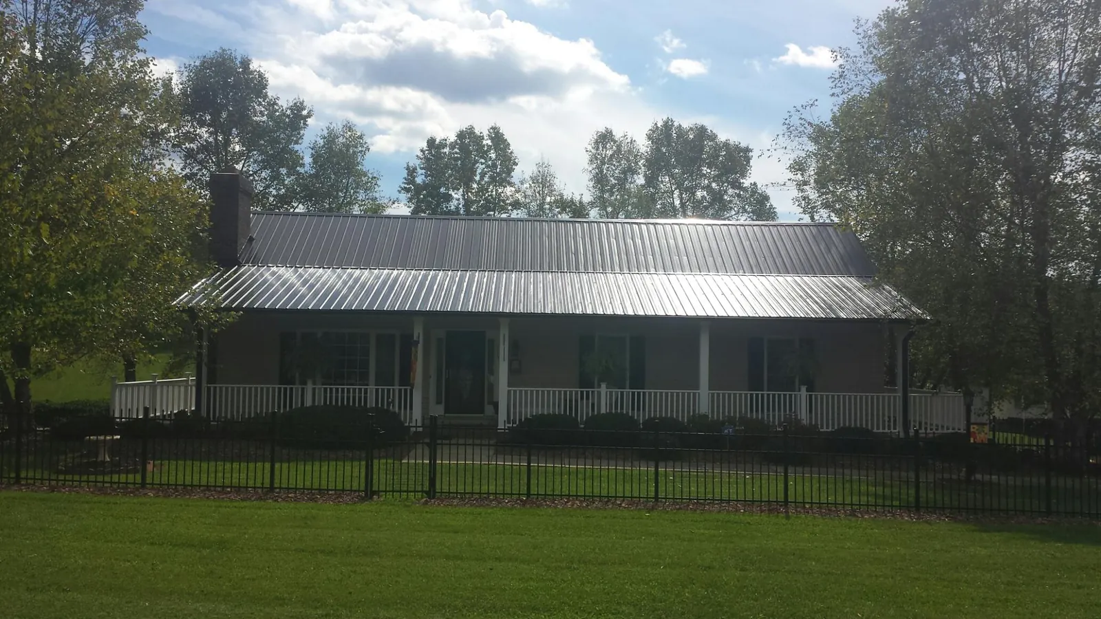 Gray metal roof on a brick ranch with a full width front porch — Gutter Guard Installation work by our crew in Centralia