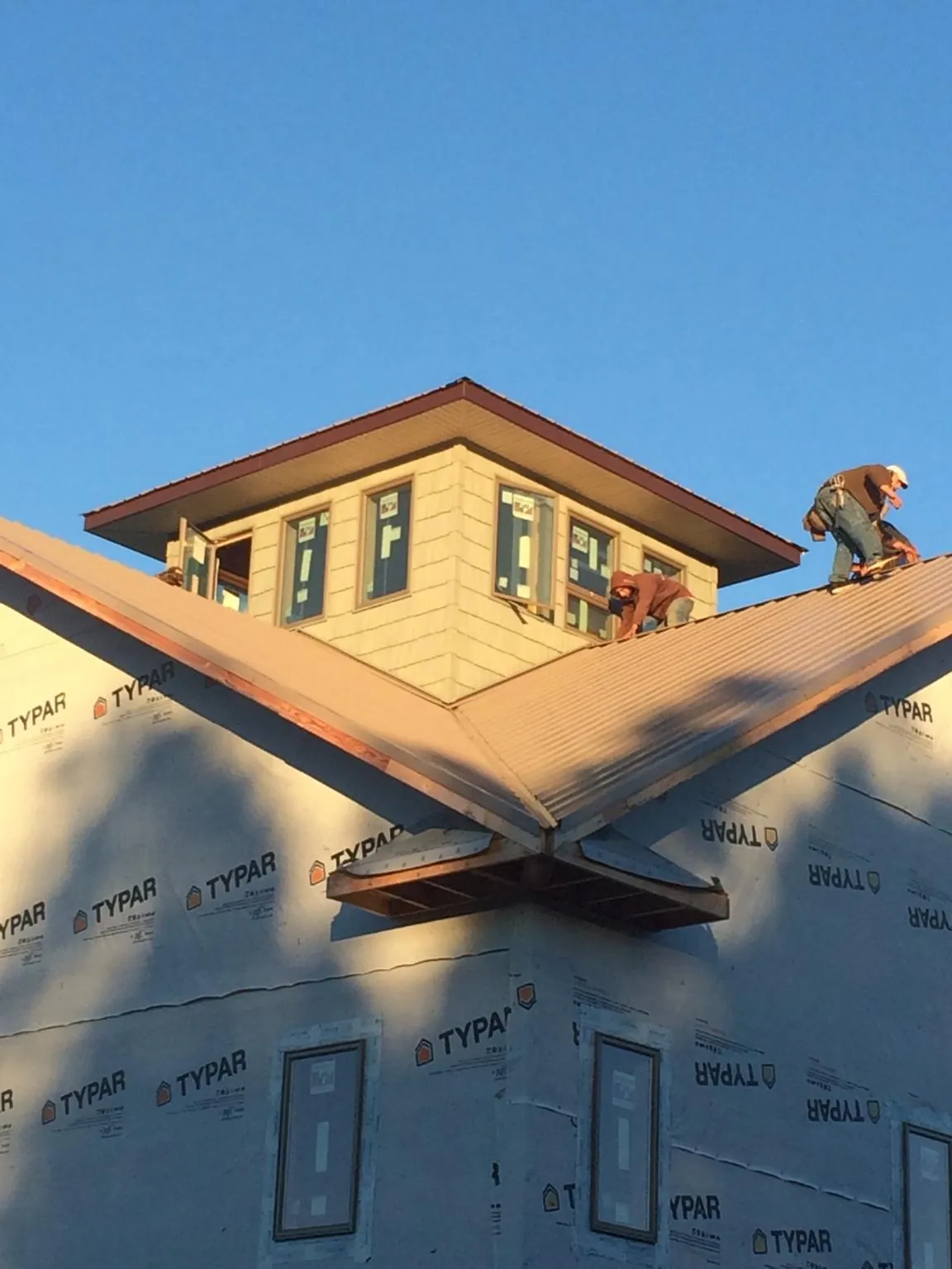 Roofers working around a rooftop cupola on a new metal roof at sunset — Roof Waterproofing in Centralia by Roofing Brothers
